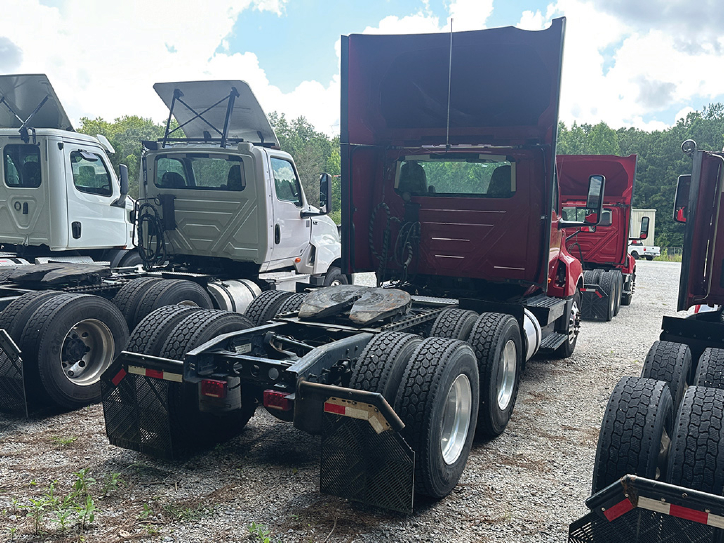 Truck chassis rear view showing fifth wheel and dual rear axles with large tires in a used class 8 daycab lineup.