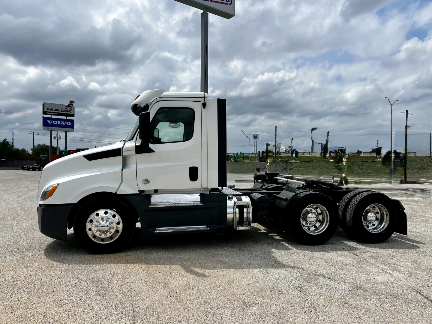 Truck cab side view of a 2020 Freightliner Cascadia 126 tractor showing front wheel, door, and fifth wheel area with chrome wheels.