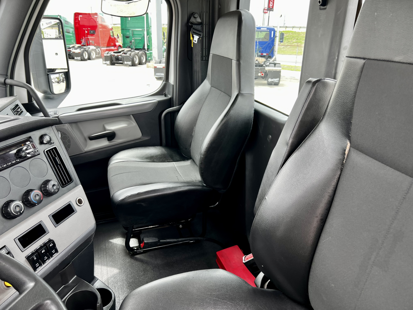 Cab interior of a Freightliner Cascadia 126 truck showing two front seats and dashboard with controls.