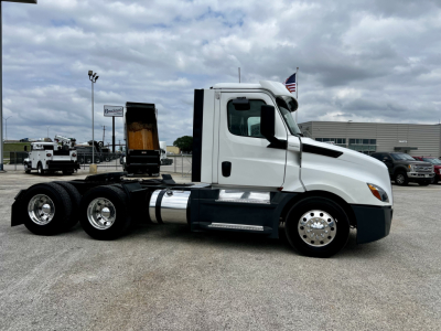 Truck side view of a 2020 Freightliner Cascadia 126 daycab, white exterior, dual rear axles, fuel tanks, chrome wheels, and a raised sleeper undercarriage area visible.