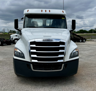 Freightliner Cascadia 126 front view showing bold chrome grille, white cab, black bumper, and side mirrors.