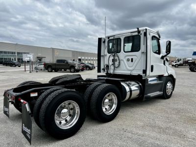 Freightliner Cascadia 126 semi truck cab and chassis side view showing rear dual axles and white cab.
