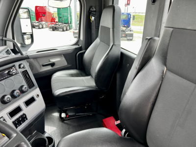 Cab interior of a Freightliner Cascadia 126 truck showing two front seats and dashboard with controls.