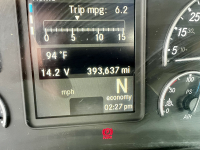 Panel display in a Freightliner Cascadia showing trip MPG 6.2, outside temp 94°F, voltage 14.2 V, mileage 393,637 mi, gear N, clock 02:27 pm.