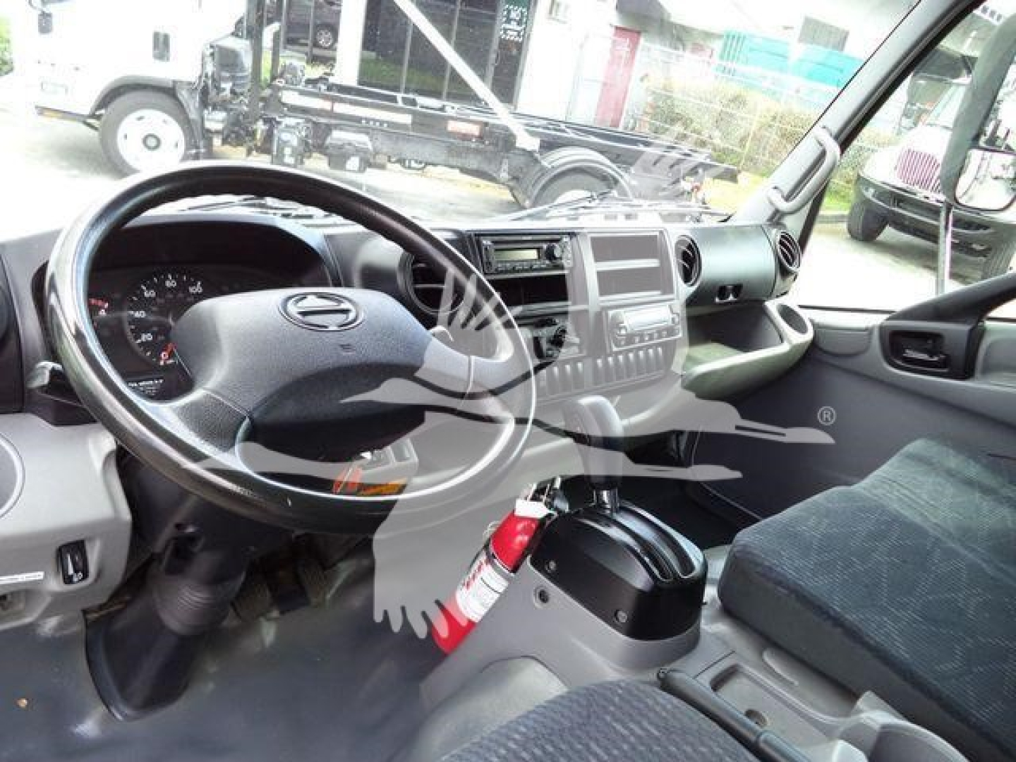 Cab interior of a 2019 Hino 195 refrigerated truck showing steering wheel, dashboard, center console, and driver's seat.