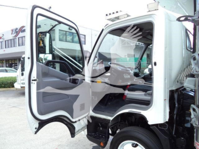 Truck cab interior view of 2019 Hino 195 refrigerated truck showing open driver door and dashboard, blank background.