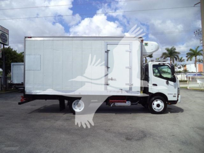 Truck side view of a 2019 Hino 195 refrigerated box truck showing a large silver cargo box with a rear access door and cab in the front.