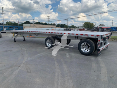 Flatbed trailer showing metal frame and wheelset with reflective safety tape and rear lights. No visible branding text readable.