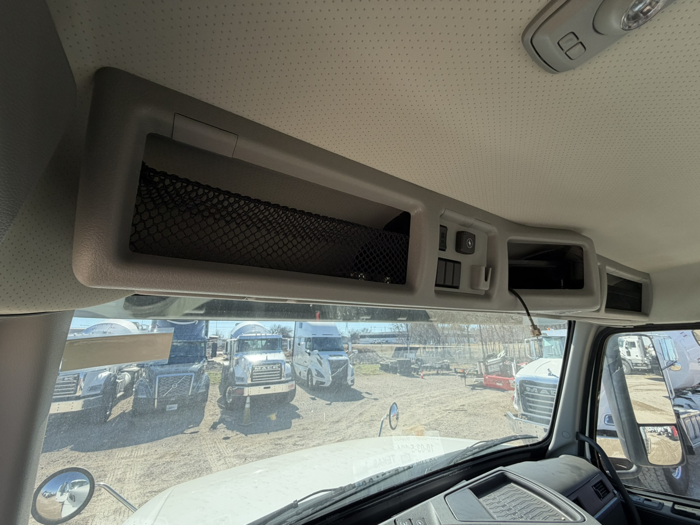 Cab and chassis interior overhead compartment with storage net and controls, view through windshield.