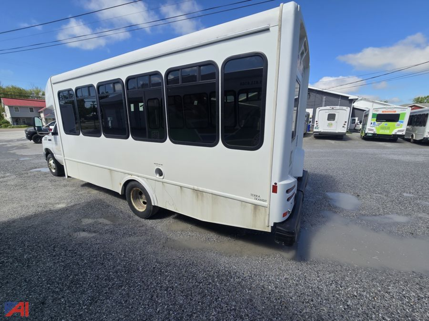 White Ford E450 wheelchair bus rear-side view showing windows and wheel with some dirt/stains.