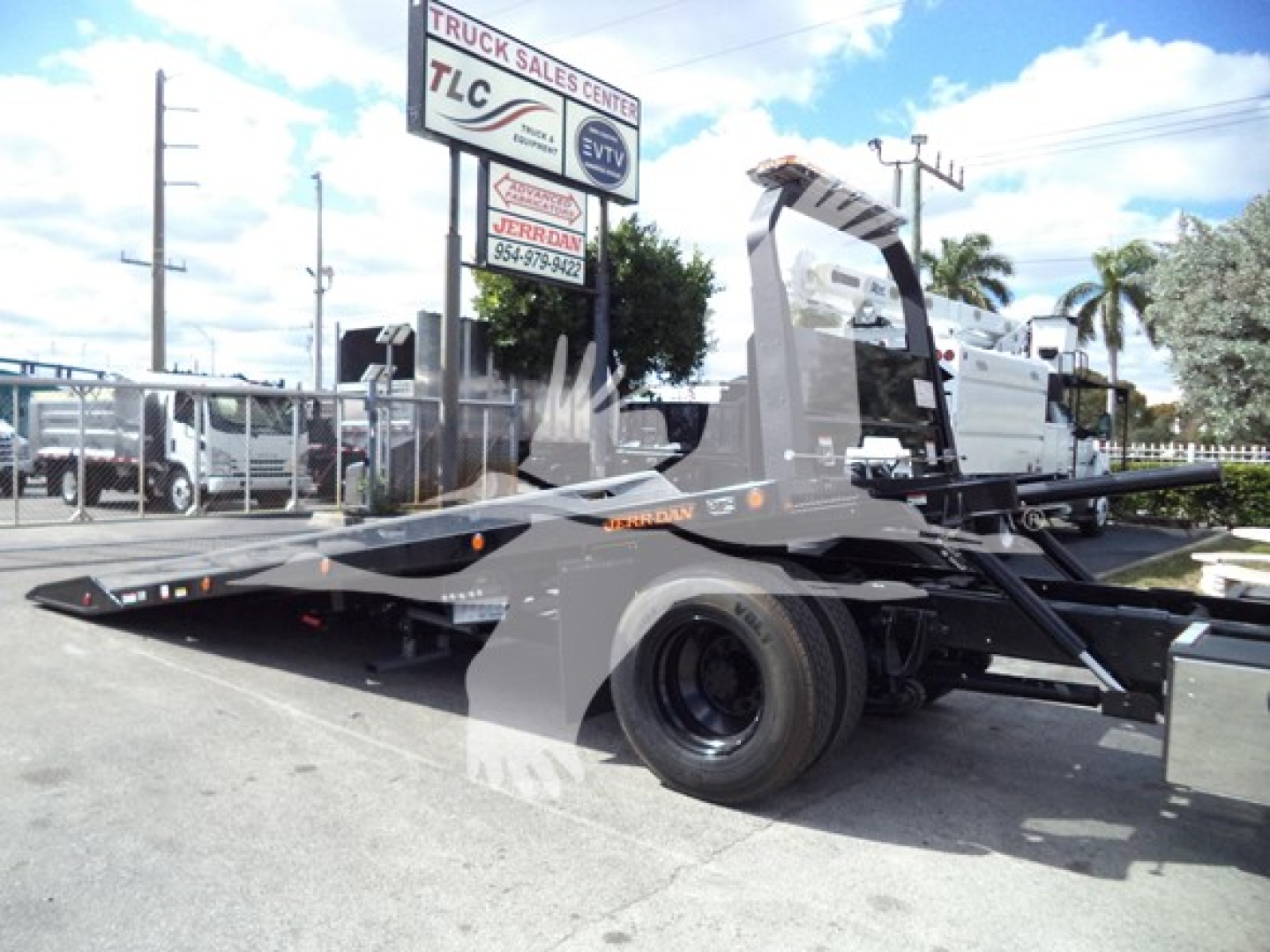2019 International Durastar 4300 rollback truck side view showing flatbed and wheel, with dealership sign in background