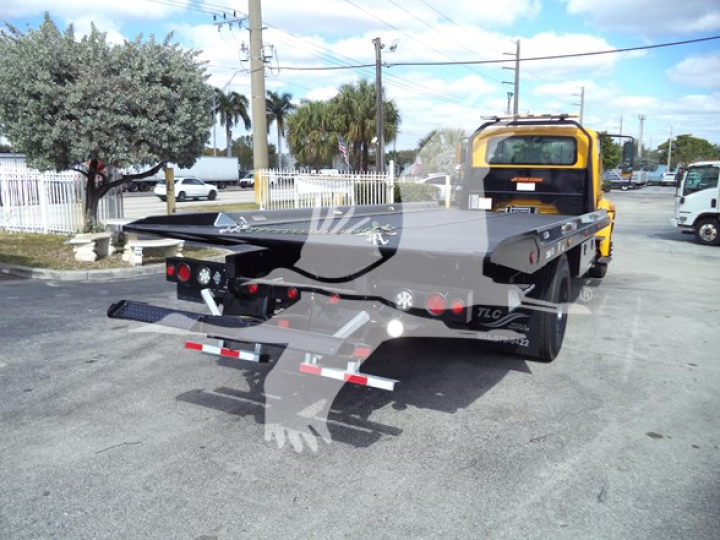 Tow truck flatbed rear view showing rollback bed and yellow cab of a 2019 International Durastar 4300.