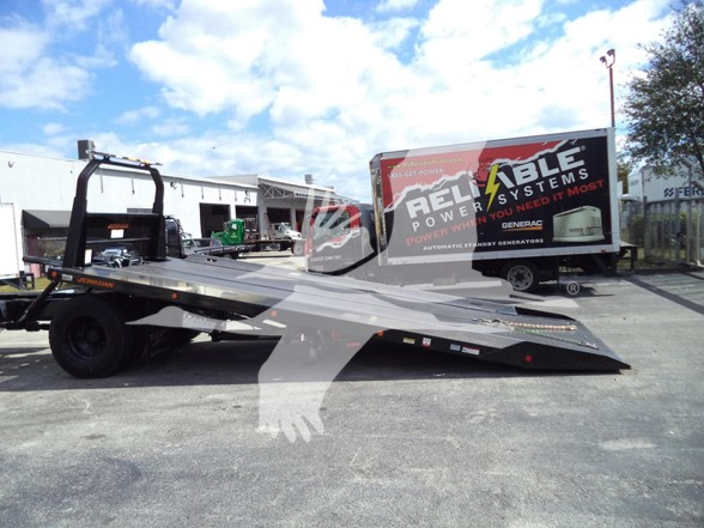  tow truck rollback flatbed truck with loading ramp and a Generac Reliable Power System trailer in background