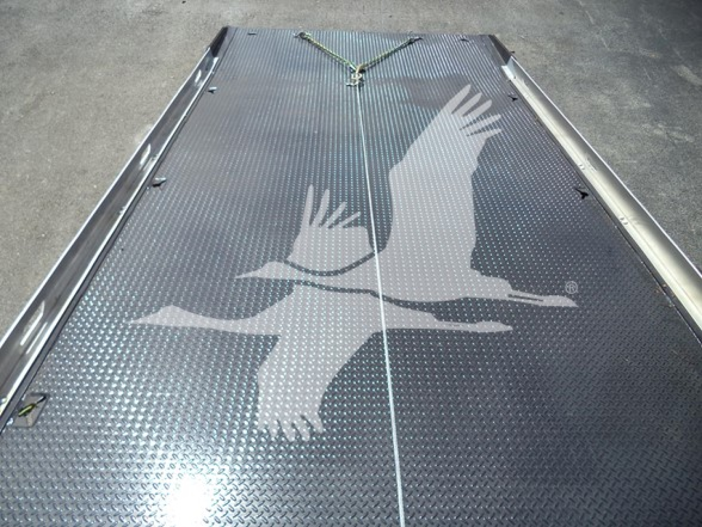 Flatbed rollback truck deck with diamond plate surface and a white bird graphic visible from top view.