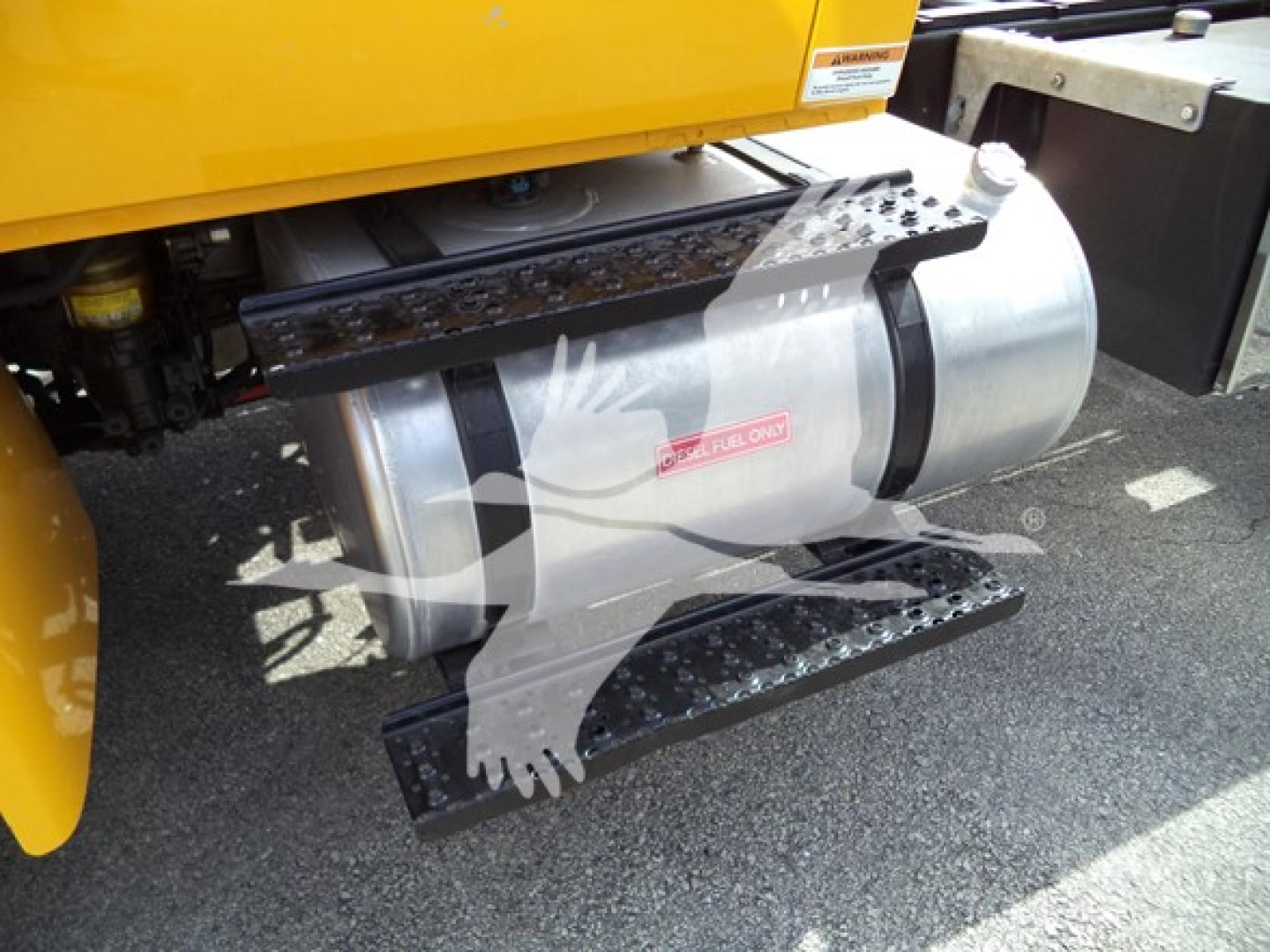 Roll-back truck side view showing metal fuel tank/step and yellow body with hydraulic components.