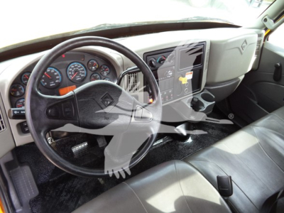 Truck cab interior showing steering wheel, dashboard gauges, center console with controls and cup holders.