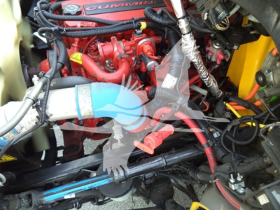 Truck engine bay with red Cummins engine, various hoses, wiring, and metal components visible.