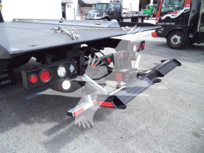 Tow truck rollback bed with hydraulic lift and rear lights visible, rear bumper and steps, metal platform, and support chains.