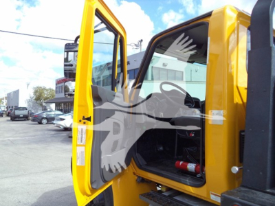Truck cab door open showing interior of 2019 International Durastar 4300 rollback truck with yellow paint and open passenger door.