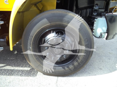 Wheel and front section of a yellow 2019 International Durastar 4300 rollback truck showing a tire with Rim, undercarriage, and body panel.