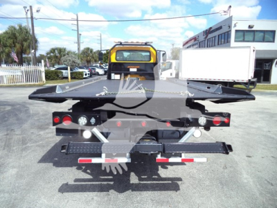 Back view of a 2019 International Durastar 4300 rollback truck with flatbed and wheel-lift, showing rear lights, bumper, and towing apparatus.