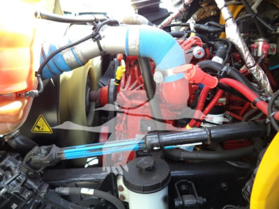 Engine bay of a 2019 International Durastar 4300 with visible hoses, connectors, and components; blue silicone hose, red hoses, black reservoir cap.