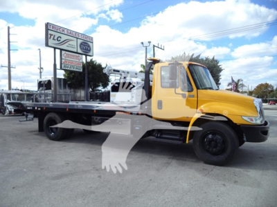 Truck: 2019 International Durastar 4300 rollback with yellow cab and black flatbed, side view showing towing equipment.