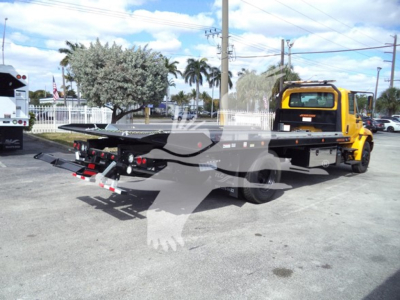 2019 International Durastar 4300 rollback truck platform viewed from rear-left side showing flatbed and tow hitch under a clear sky.