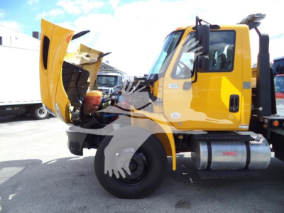 Truck cab with hood open showing engine bay and side view of International Durastar 4300 rollback truck, yellow paint, exposed engine area.