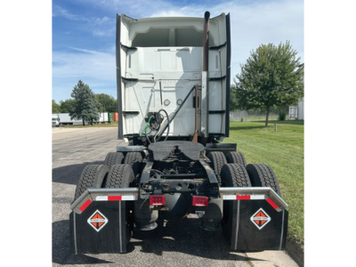 Truck rear showing fifth wheel area and dual rear axles with black mud flaps and reflective safety decals.