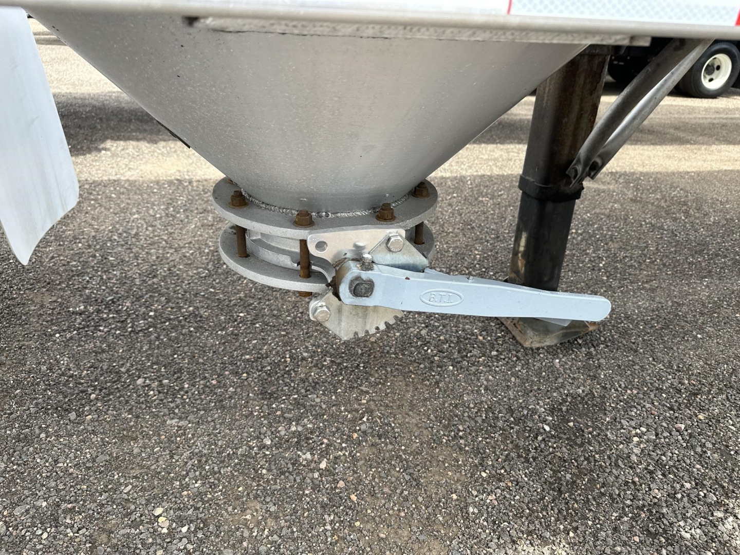 Pneumatic trailer component showing a gravity drop with a clamped discharge valve and lever in view.