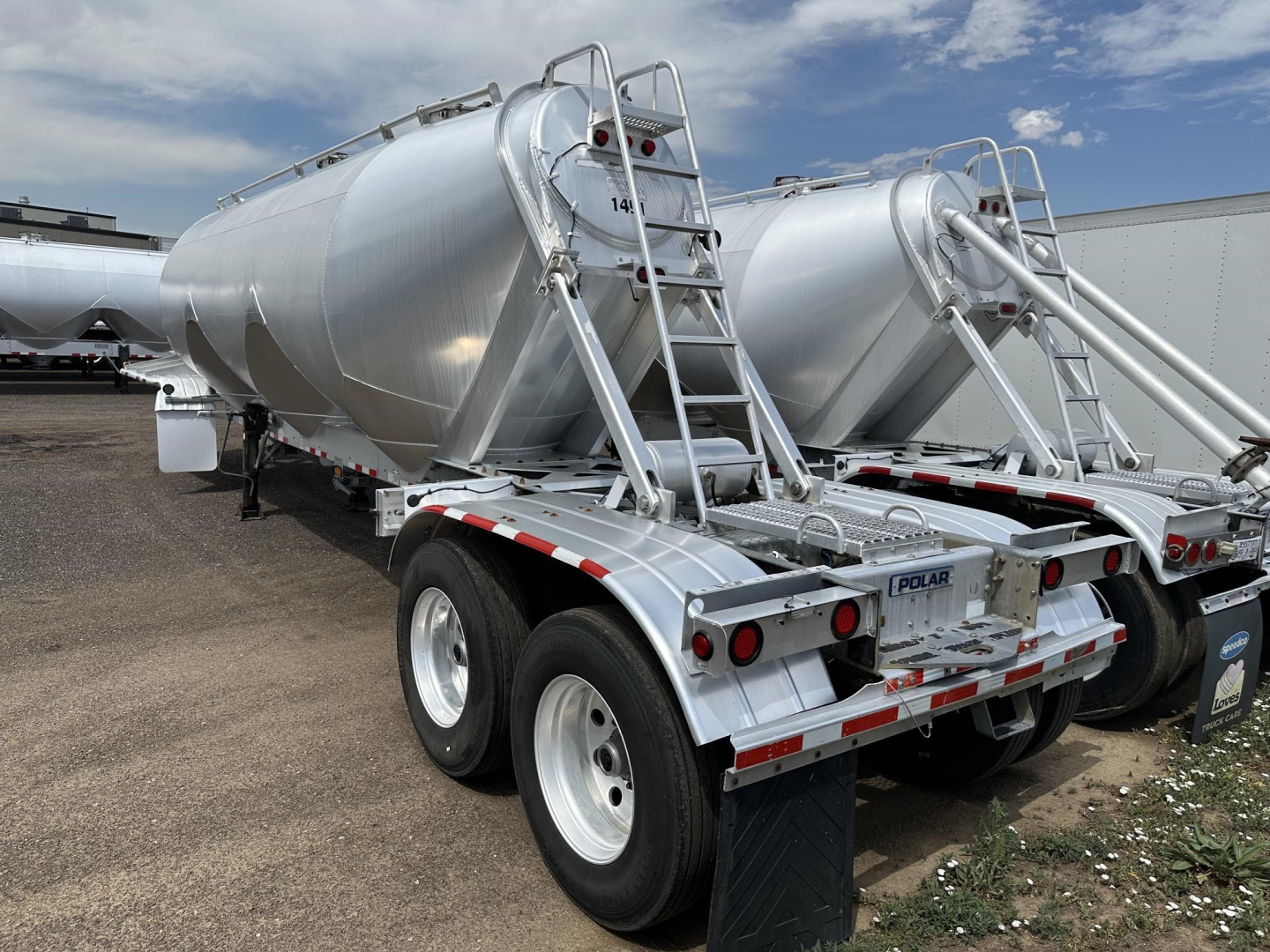 Dual-axle Polar gravity drop pneumatic trailer showing polished aluminum tank and rear ladder with safety rails.