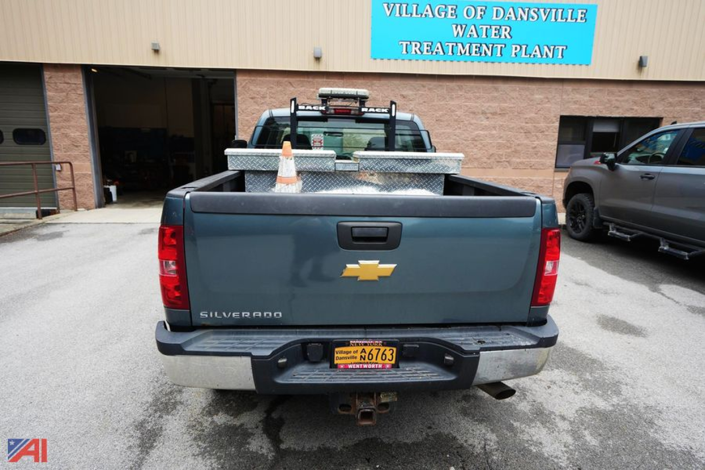 Rear view of a blue 2013 Chevrolet Silverado 2500 pickup showing Chevrolet tailgate emblem, spare tire rack, and NY license plate.