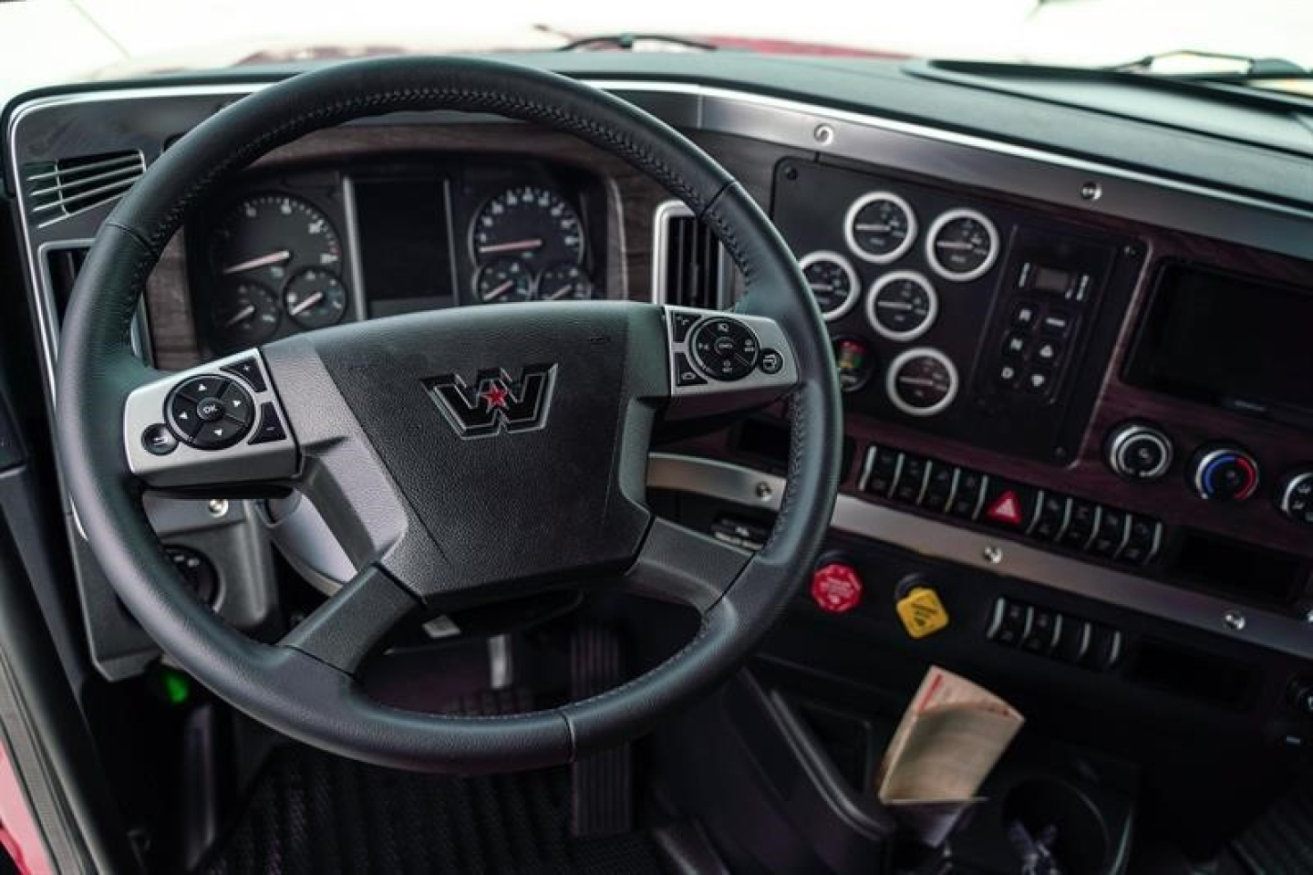 Truck cockpit showing Western Star steering wheel and gauges with dashboard controls.