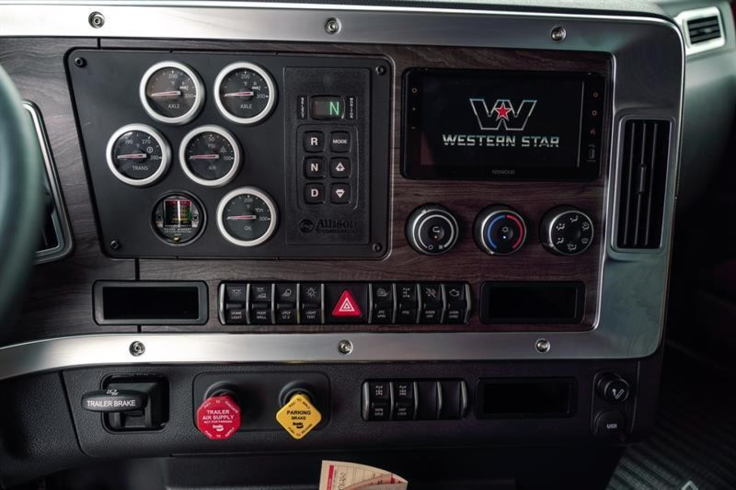 Dashboard panel of a Western Star 47X truck showing multiple gauges, digital display with Western Star logo, climate controls, and various switches.