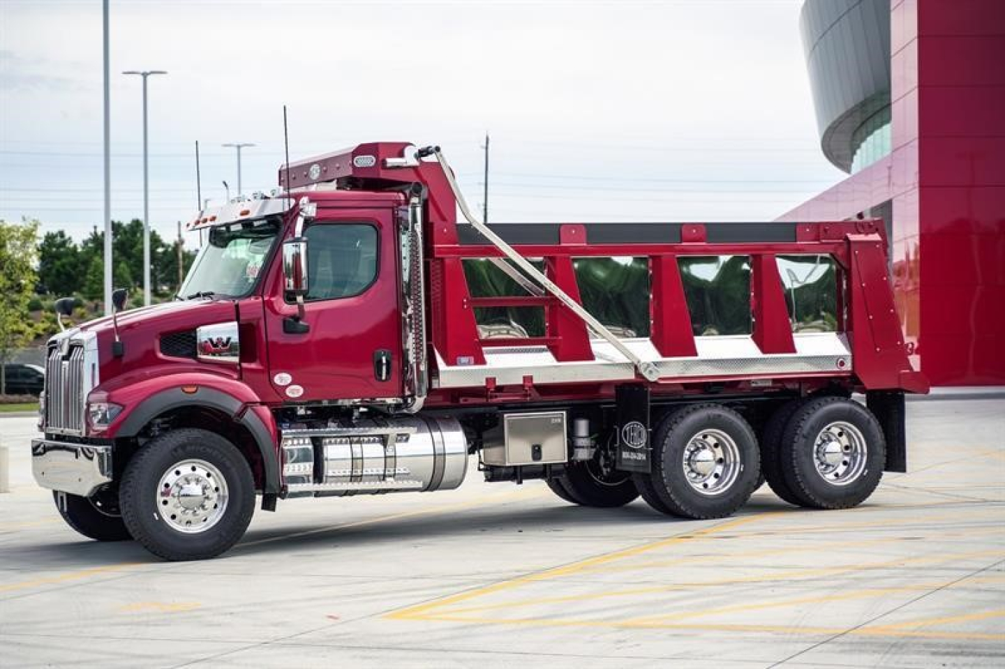 Western Star 47X dump truck in maroon showing side view with dump bed and chrome exhaust stack.