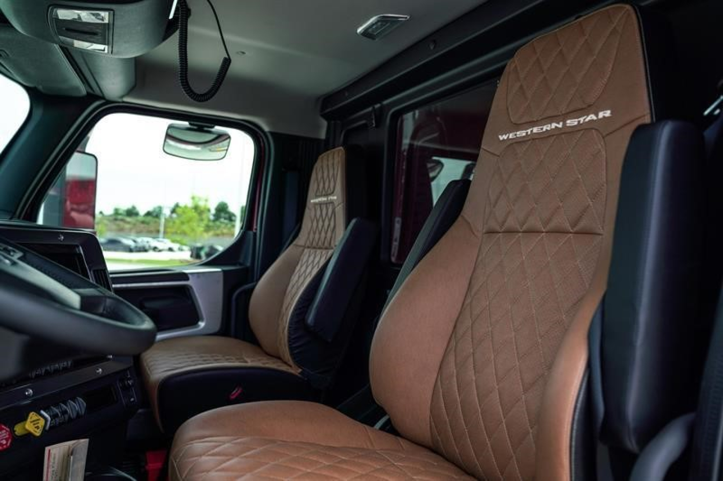 Interior of a 2027 Western Star 47X dump truck showing tan diamond-stitched seats with Western Star branding in cab and driver seat.