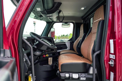Interior cab of a new Western Star 47X dump truck showing driver seat, steering wheel, dashboard, and passenger seat with tan upholstery.