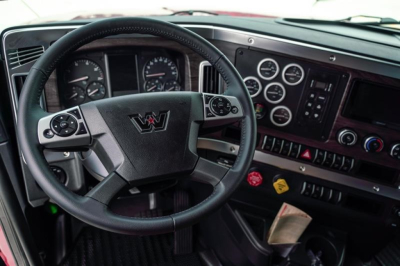 Truck cockpit showing Western Star steering wheel and gauges with dashboard controls.