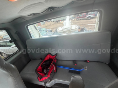 Interior cab of a 2004 International 4300 truck showing gray rear bench seat and a red tool bag with blue and metal tools on the seat.