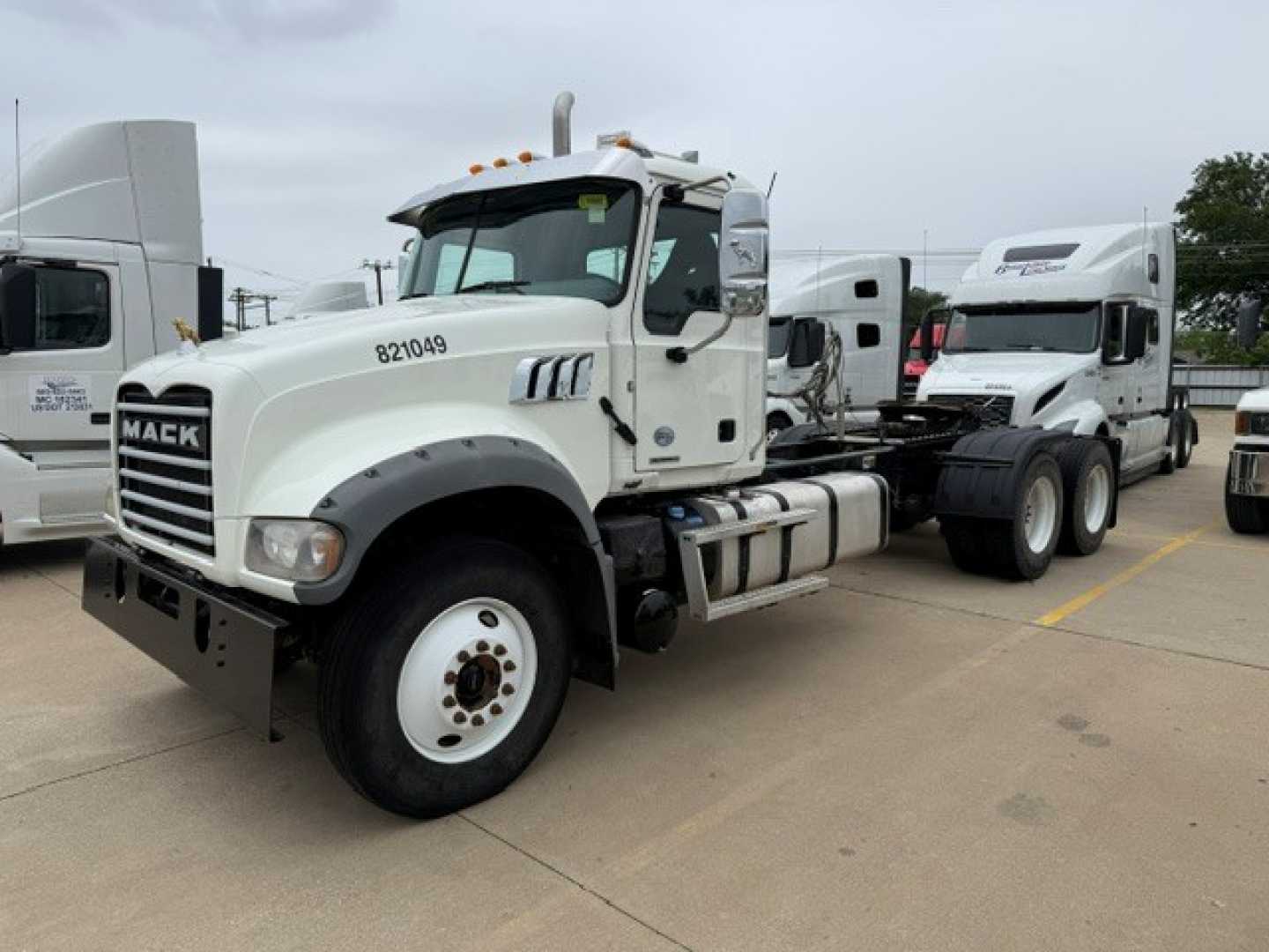 Mack GR64FT truck in a lot showing front-left side with white cab, chassis, and dual rear axles; stock number 8721049 painted on door; VIN and B3634L listing details in image.