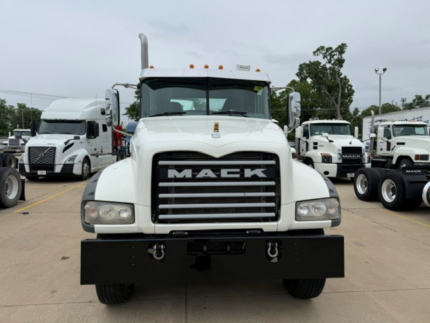 Mack GR64FT conventional daycab truck front view showing large black grille with MACK letters, white cab, bumper, and headlights.