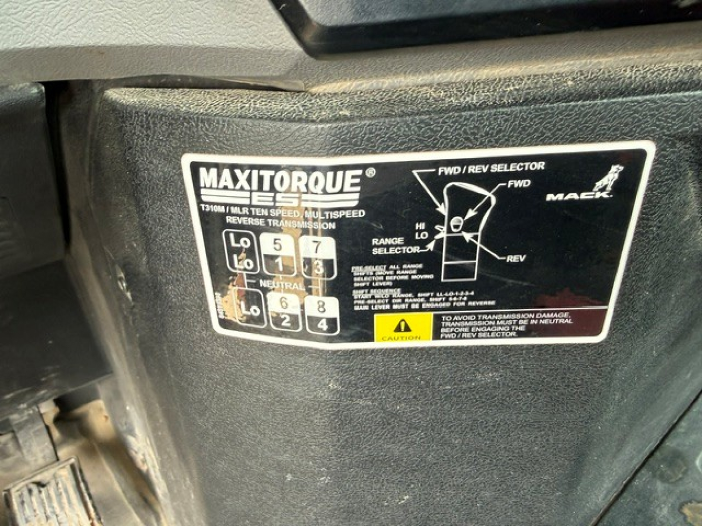 Mack GR64FT cab interior area showing MaxiTorque transmission shift diagram label with gear pattern and FWD/REV selector.