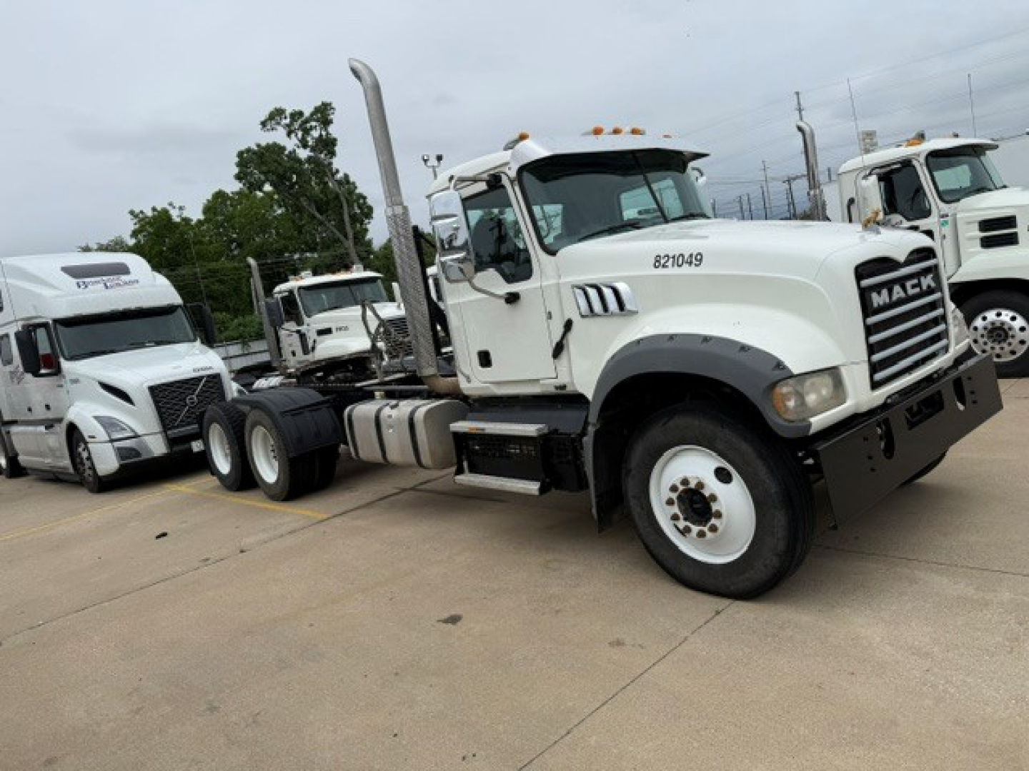 Mack GR64FT truck in service view showing front grille with Mack lettering and vertical exhaust stack.