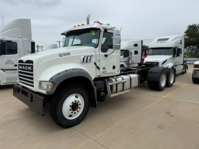 Mack GR64FT truck in a lot showing front-left side with white cab, chassis, and dual rear axles; stock number 8721049 painted on door; VIN and B3634L listing details in image.