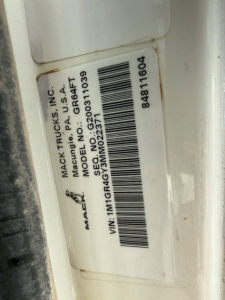 Label on Mack truck door jamb with VIN, stock number, model, and serial/barcode information. Text includes: MACK TRUCKS INC., MODEL NO. MD?  U.S.A. MADE IN USA, VIN: 1M1GR4GY3MM022371, SERIAL NO. 9203010303, STOCK NO. 84811604, SEQ NO. 2?  
