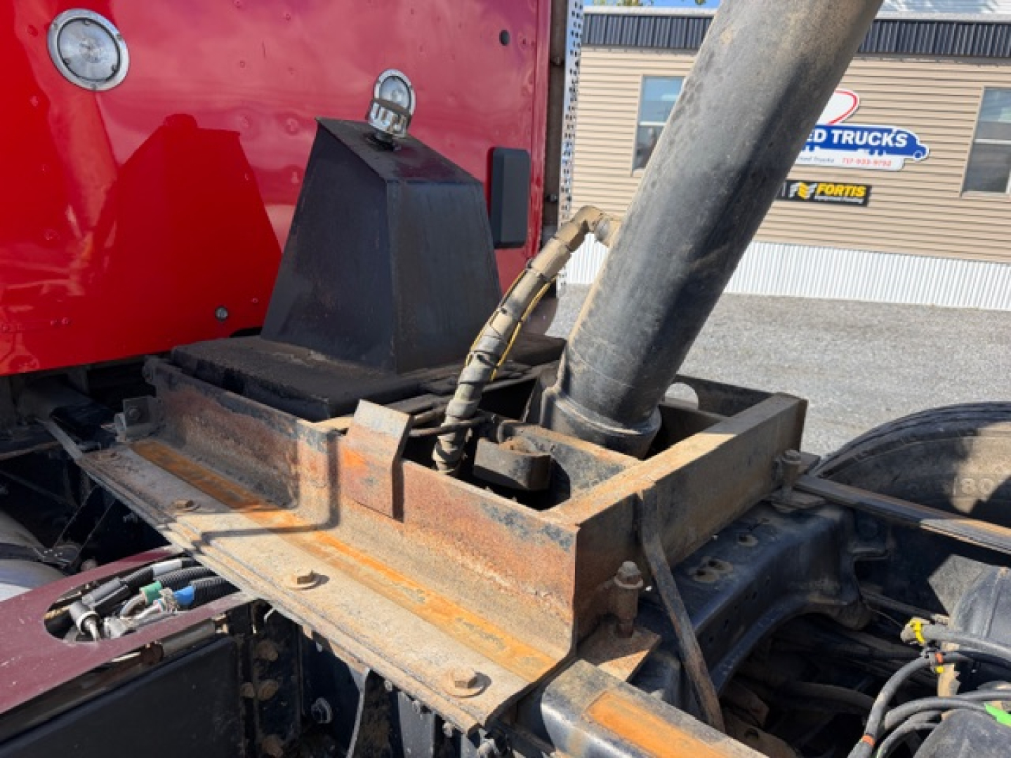 Kenworth T880 chassis showing hydraulic ballast and rusty metal components around the fifth wheel and frame