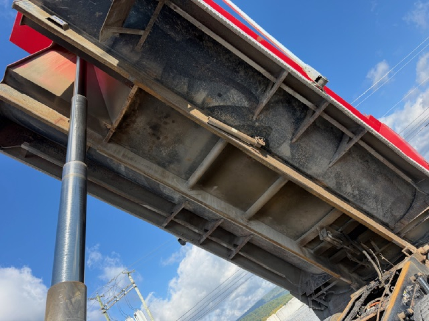 Kenworth T880 dump truck bed with hydraulic lift and underside view, chrome hydraulic cylinder visible.