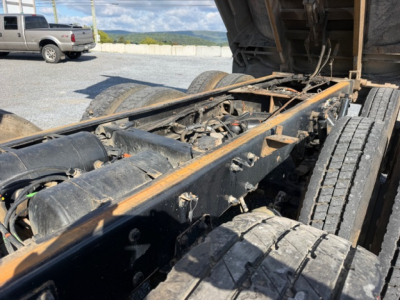 Kenworth T880 chassis and dump bed visible, wheel tires, exposed frame rails, drivetrain and hydraulic components in the truck’s undercarriage