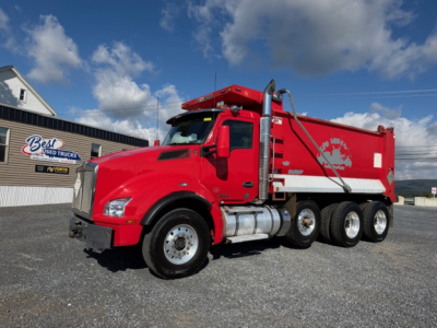 Kenworth T880 dump truck in red with white dump body, side view showing fuel tanks and wheels.